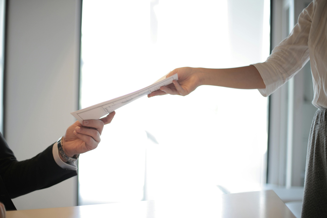 An image of someone handing a landlord rental applications and supporting documents