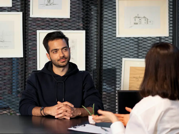 An image of someone interviewing another person across from them at a table.